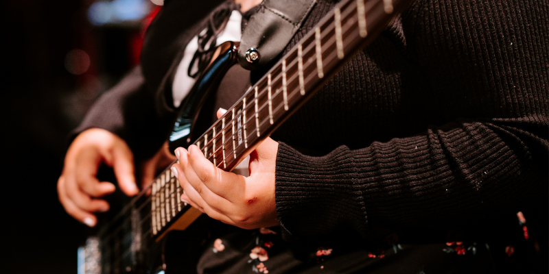 a close up picture of a woman playing guitar